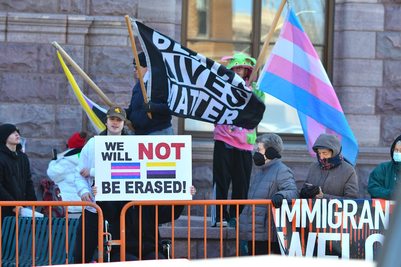 Protesters holding LGBTQ+ and BLM flags, advocating for rights and inclusion.