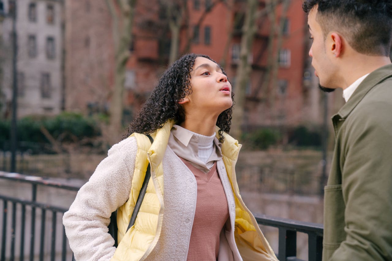 A young couple having an intense conversation outdoors, showcasing a moment of conflict.